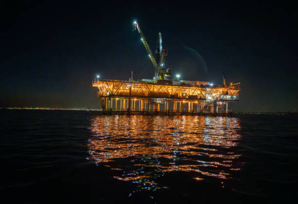 Night-time aerial view showcases the Esther platform, an offshore fracking drill rig located in the Pacific Ocean near Los Angeles, illuminating the dark waters.